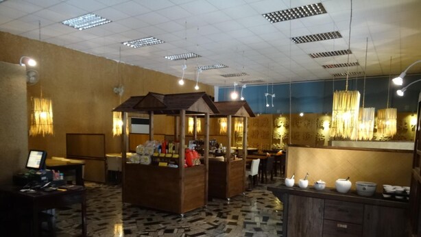 Un vestíbulo de hotel con suelo de mosaico, mostradores de madera y una zona de estar.