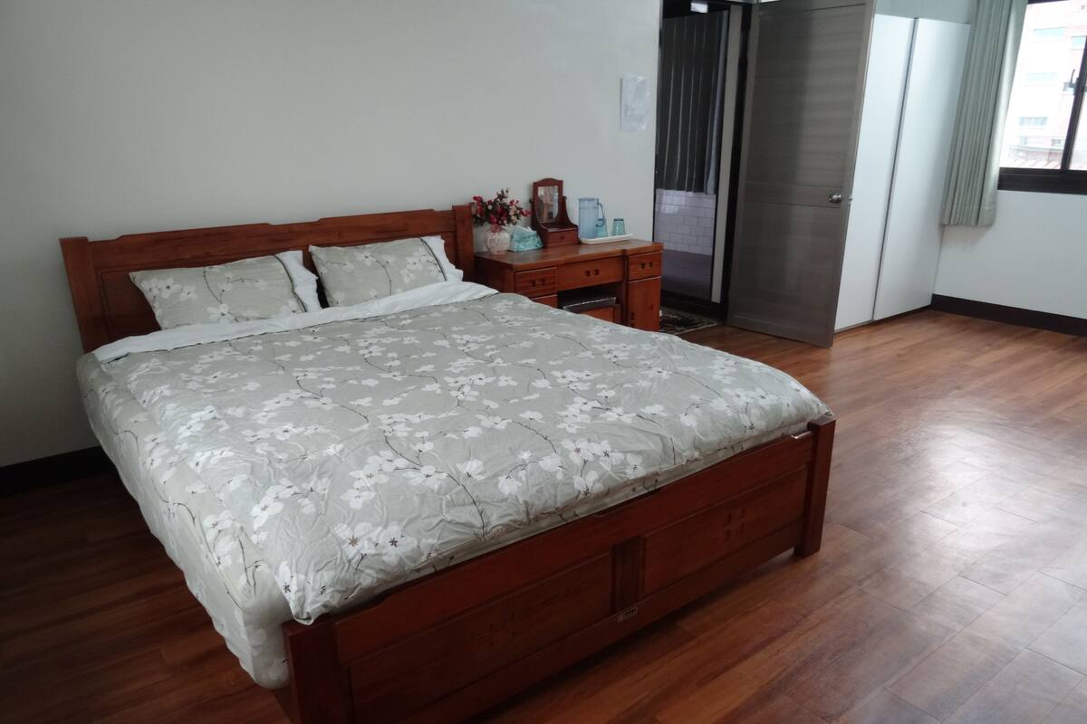 Quarto com cama de madeira, mesa de cabeceira e guarda-roupa.