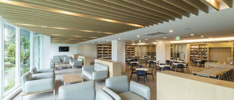Una biblioteca moderna con zonas de estar, estanterías y techo de madera.