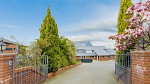 A gated driveway leading to a house with a sloped roof and a brick wall. - Superior Dunedin Apartments (Dunedin)