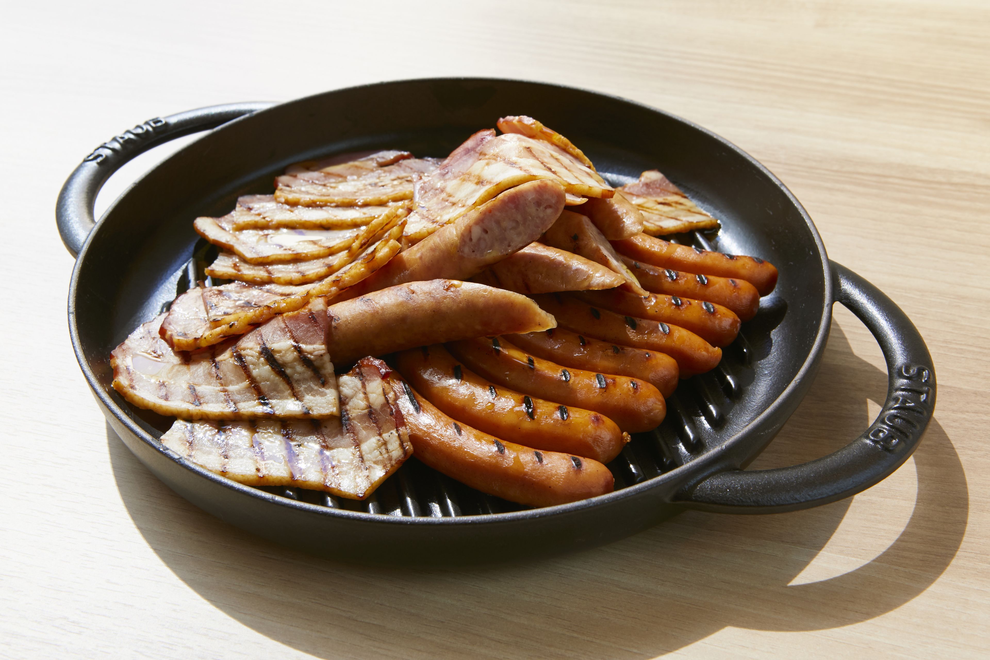 A cast iron skillet with grilled meat and sausages.