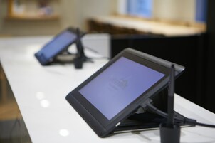 A tablet on a stand with a screen displaying "INTERGATE" on a white table.