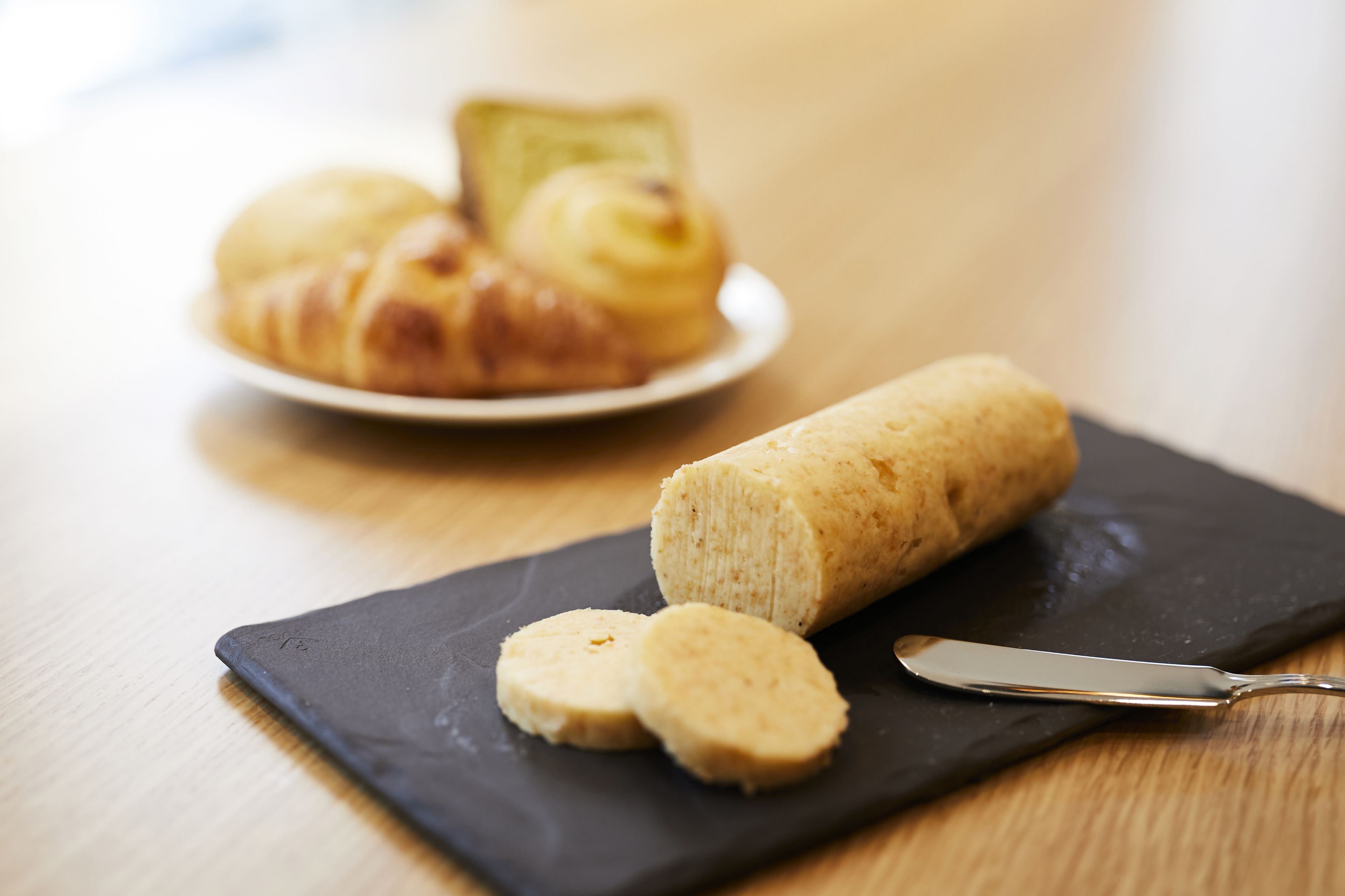 A loaf of bread and a plate with croissants on a wooden table.
