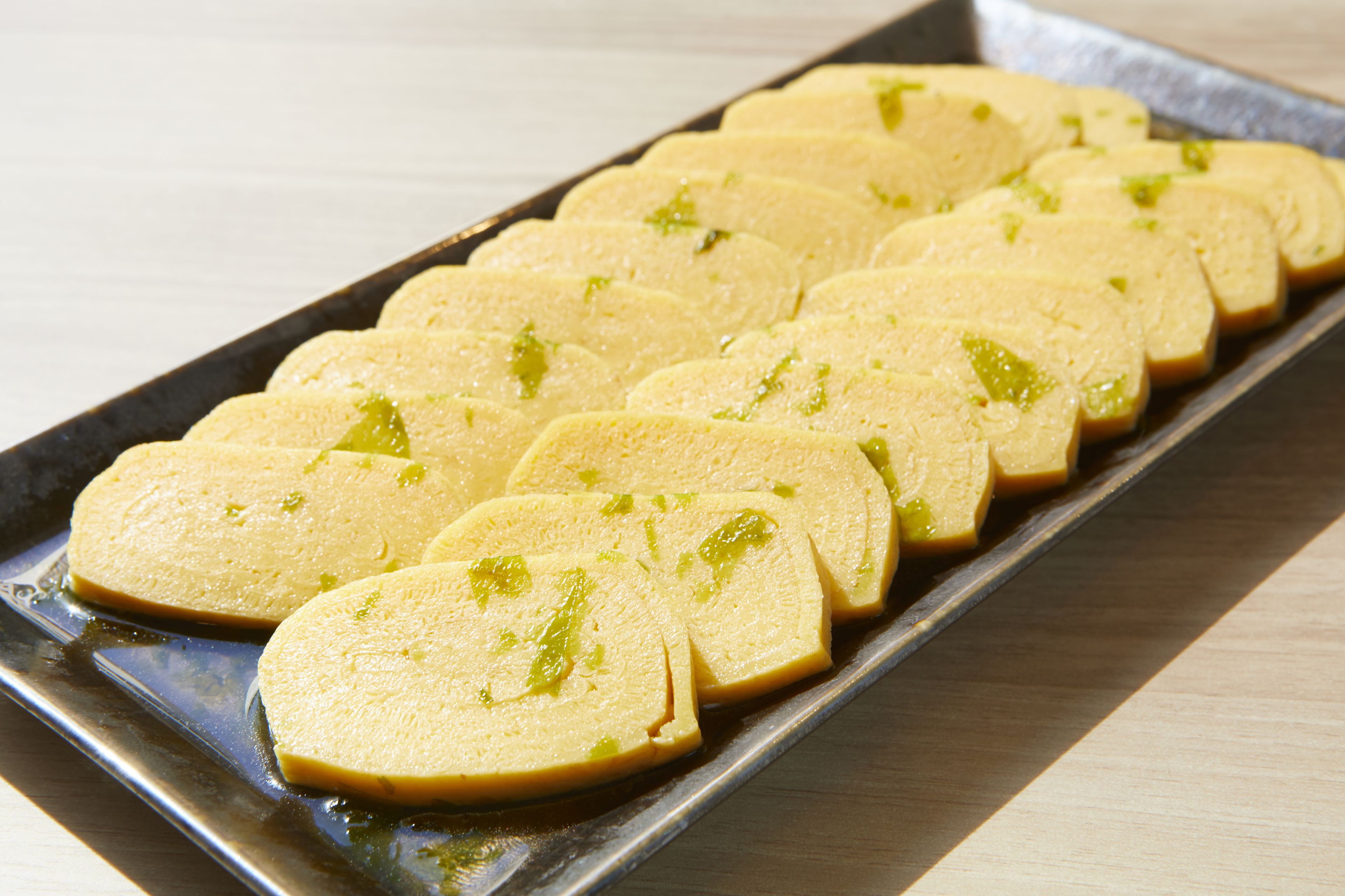A tray of sliced bread with green toppings.