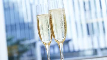 Two champagne flutes on a reflective surface with a blurred background of vertical lines, possibly a window or wall.