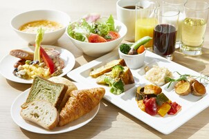 A breakfast setting with various dishes including toast, croissants, vegetables, and beverages.