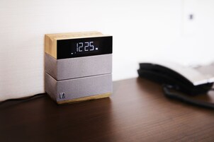 Un reloj digital de diseño en madera y gris sobre una superficie de madera.