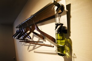 Un perchero de madera con varios ganchos y una botella de aceite de oliva en la pared.