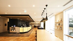 Un intérieur moderne avec un comptoir d’accueil en bois, un long comptoir et un espace détente avec des chaises.
