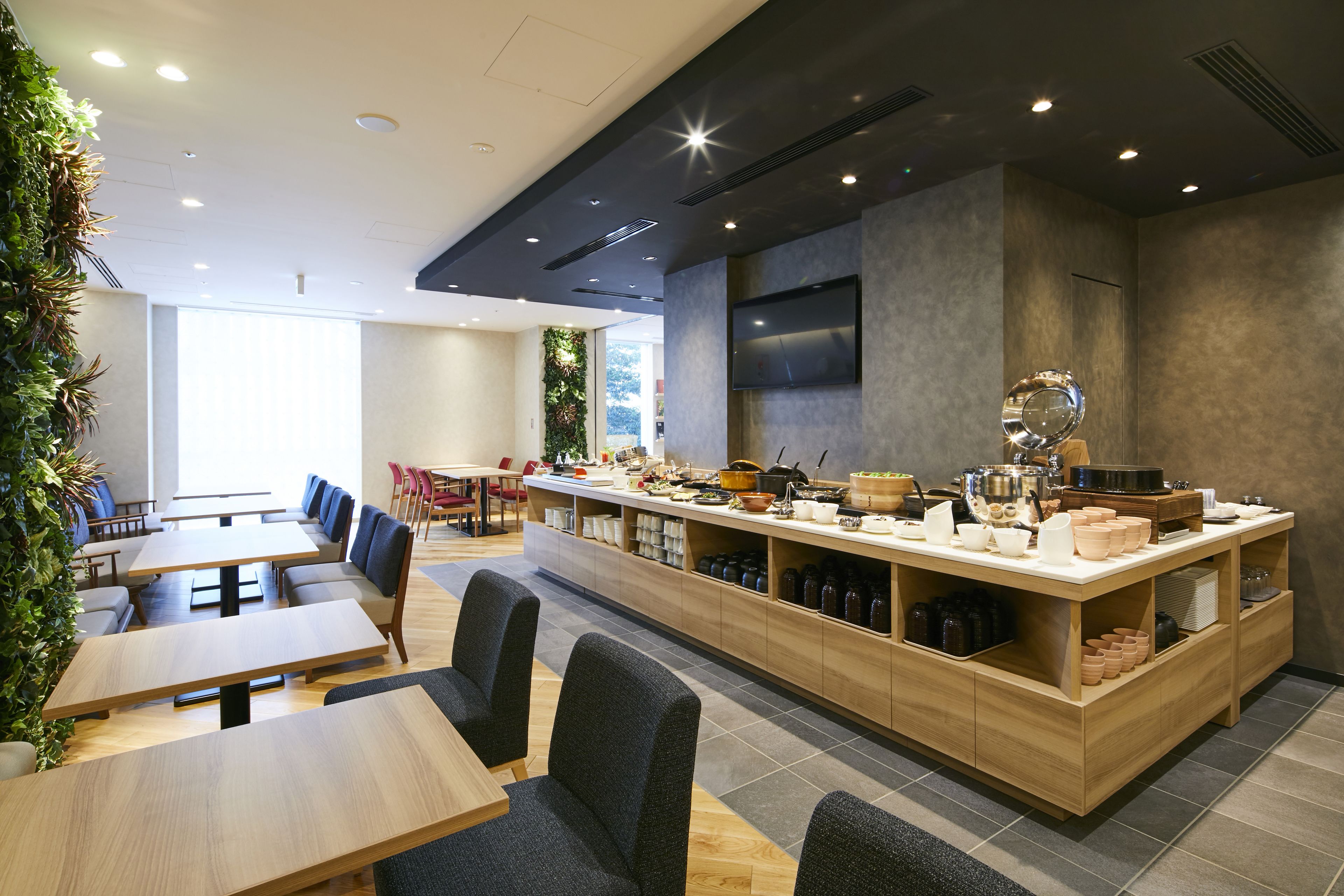 A modern restaurant with a long counter, seating area, and a large window.