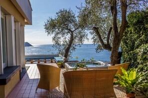 Ein Balkon mit Korbstühlen, einem Whirlpool und Blick auf das Meer.