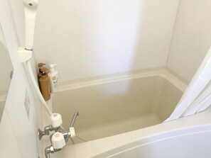 A bathroom with a bathtub, a shower, and a toilet. There are toiletries on the wall.