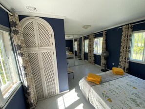 Un dormitorio con cama, ventilador y ventana con cortinas.