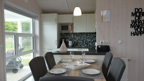Un comedor con una mesa de madera preparada para cuatro, una cocina al fondo y una cita motivacional en la pared.