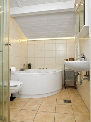 Bathroom features a curved bathtub, toilet, and sink with a mirror above.