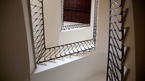 Una escalera con barandillas de metal y un pequeño ventanal en la parte superior.