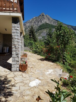 A stone building with a balcony, a stone pathway, and a mountainous backdrop. - Val D'Allos mountain chalet for 8 people (Villars-Colmars)