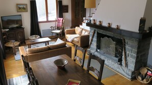 A cozy living room with a fireplace, wooden furniture, and a television. - Val D'Allos mountain chalet for 8 people (Villars-Colmars)