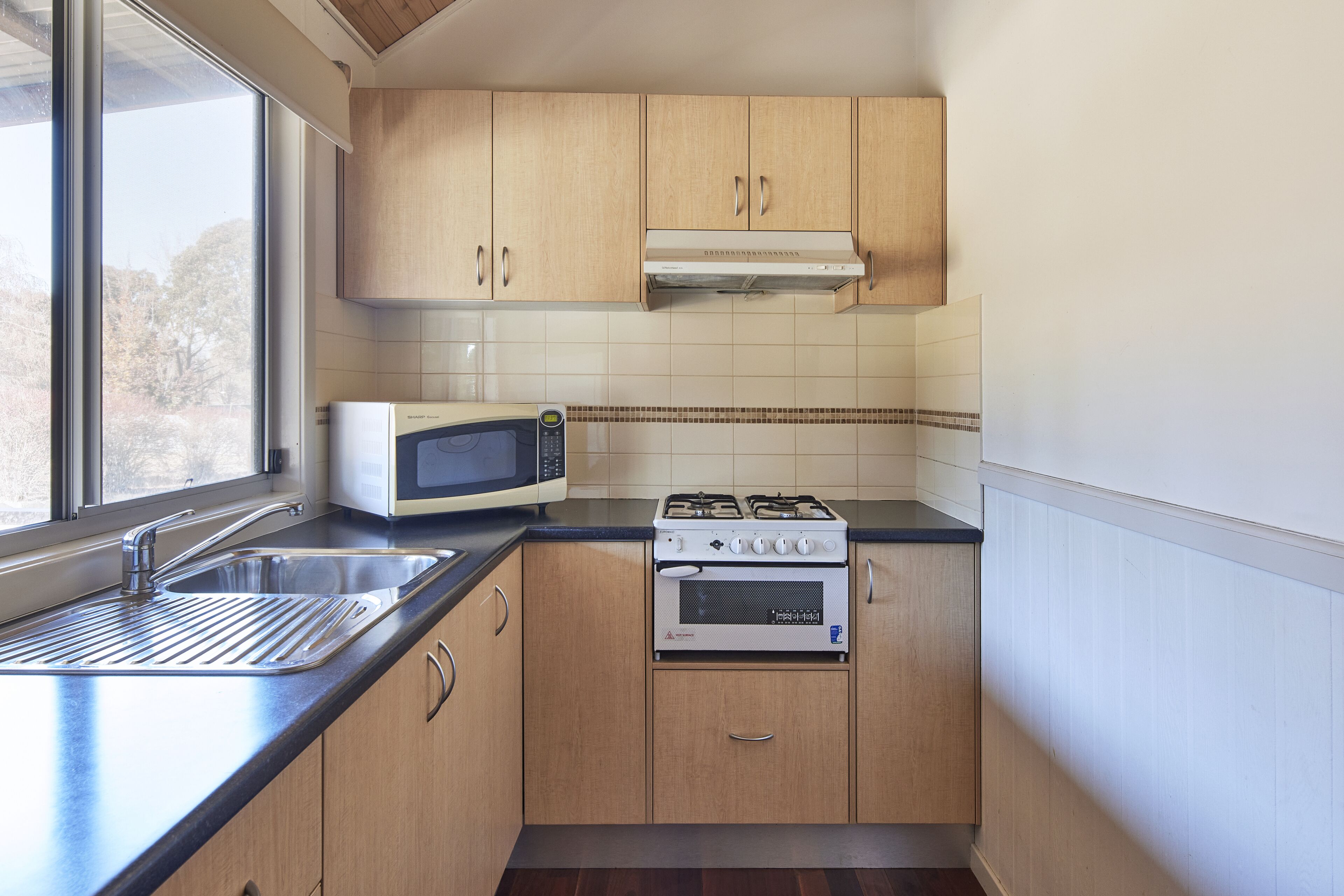 Cocina compacta con microondas, estufa y lavamanos.