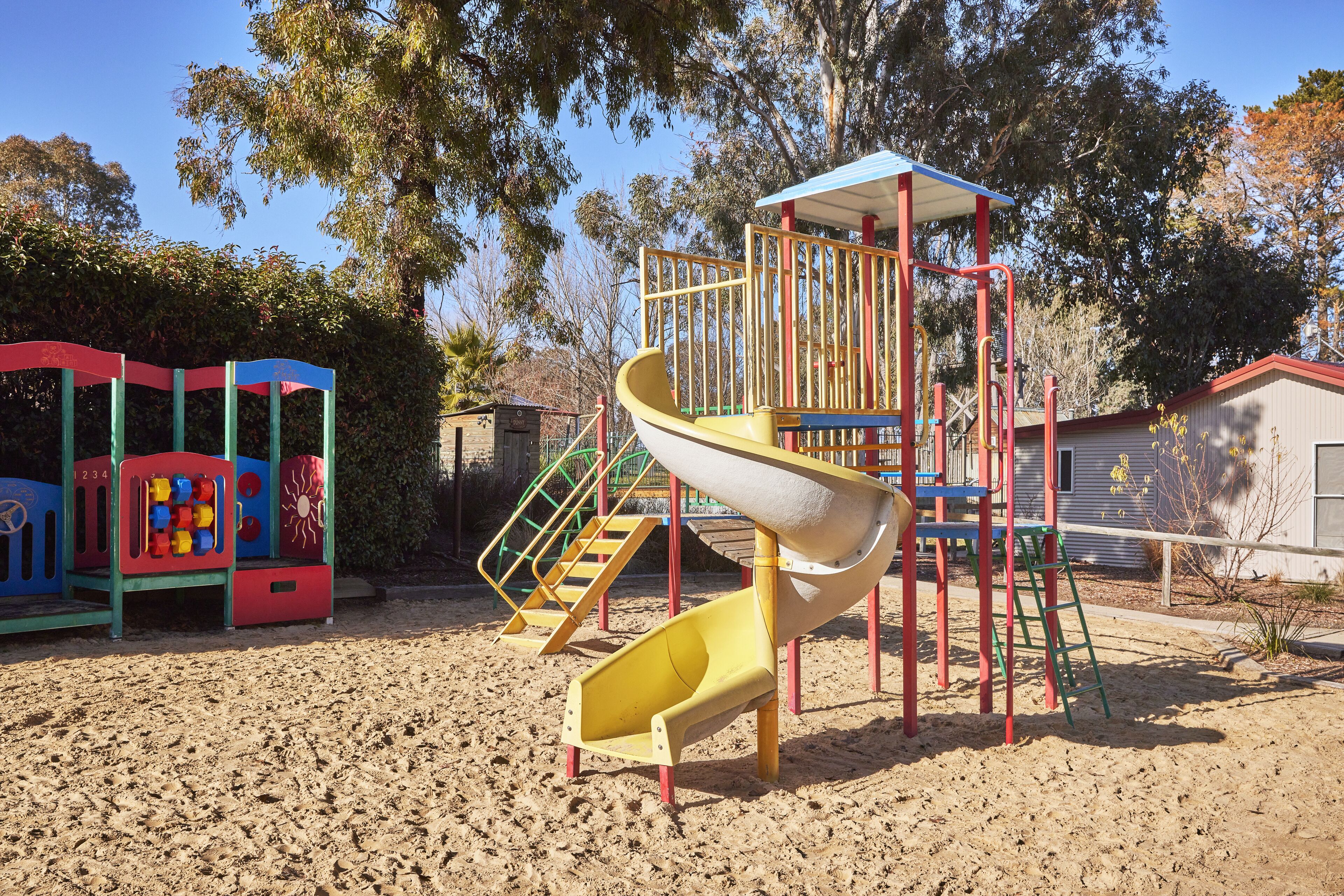 A playground with a yellow slide, climbing structures, and colorful play equipment.