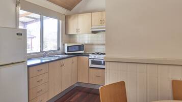 A kitchen with wooden cabinets, a microwave, a stove, and a refrigerator.