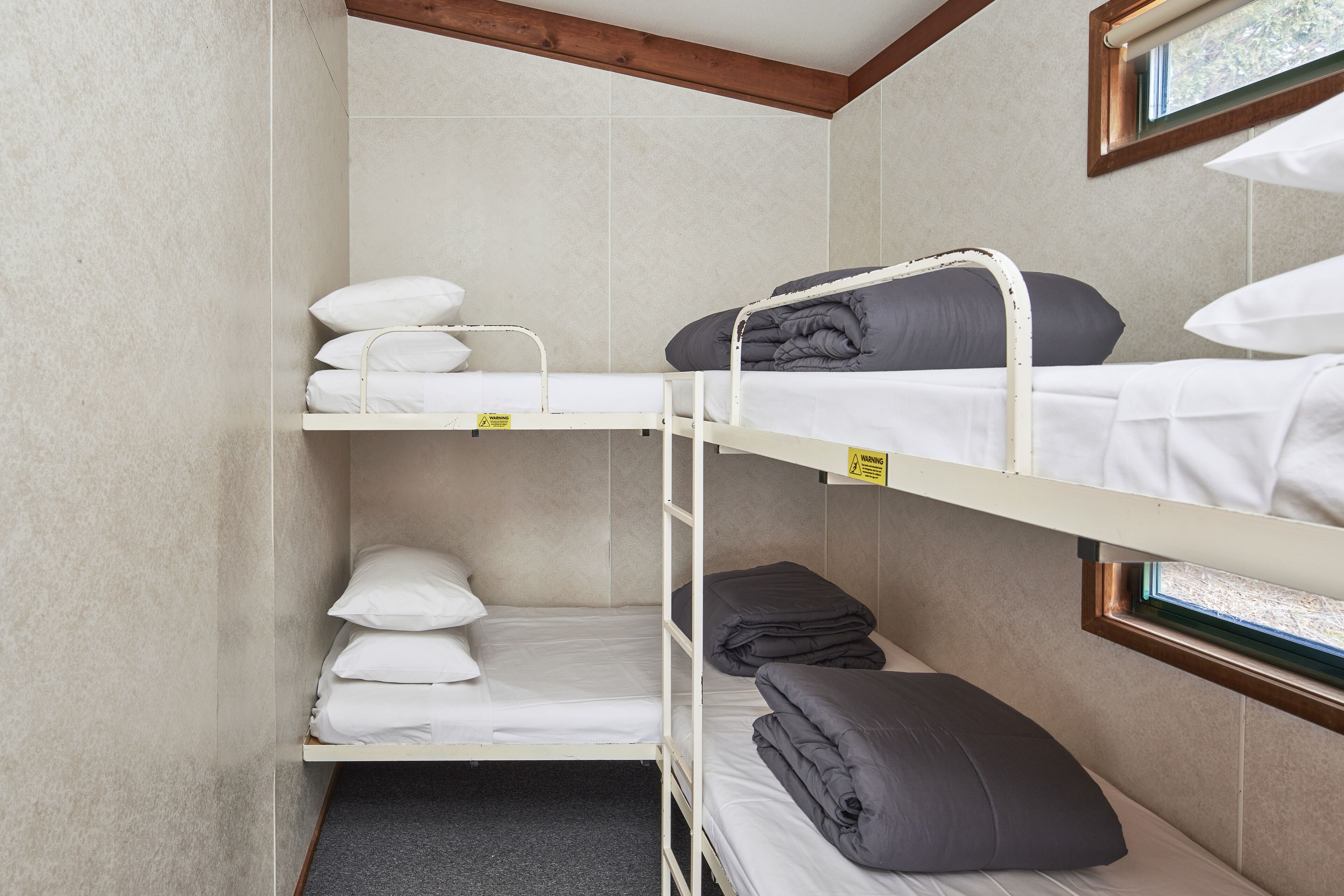 Habitación con literas de dos niveles, cada una con almohadas y mantas.