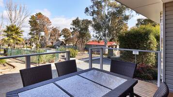 An outdoor patio with wicker furniture and a view of a park and buildings in the background.