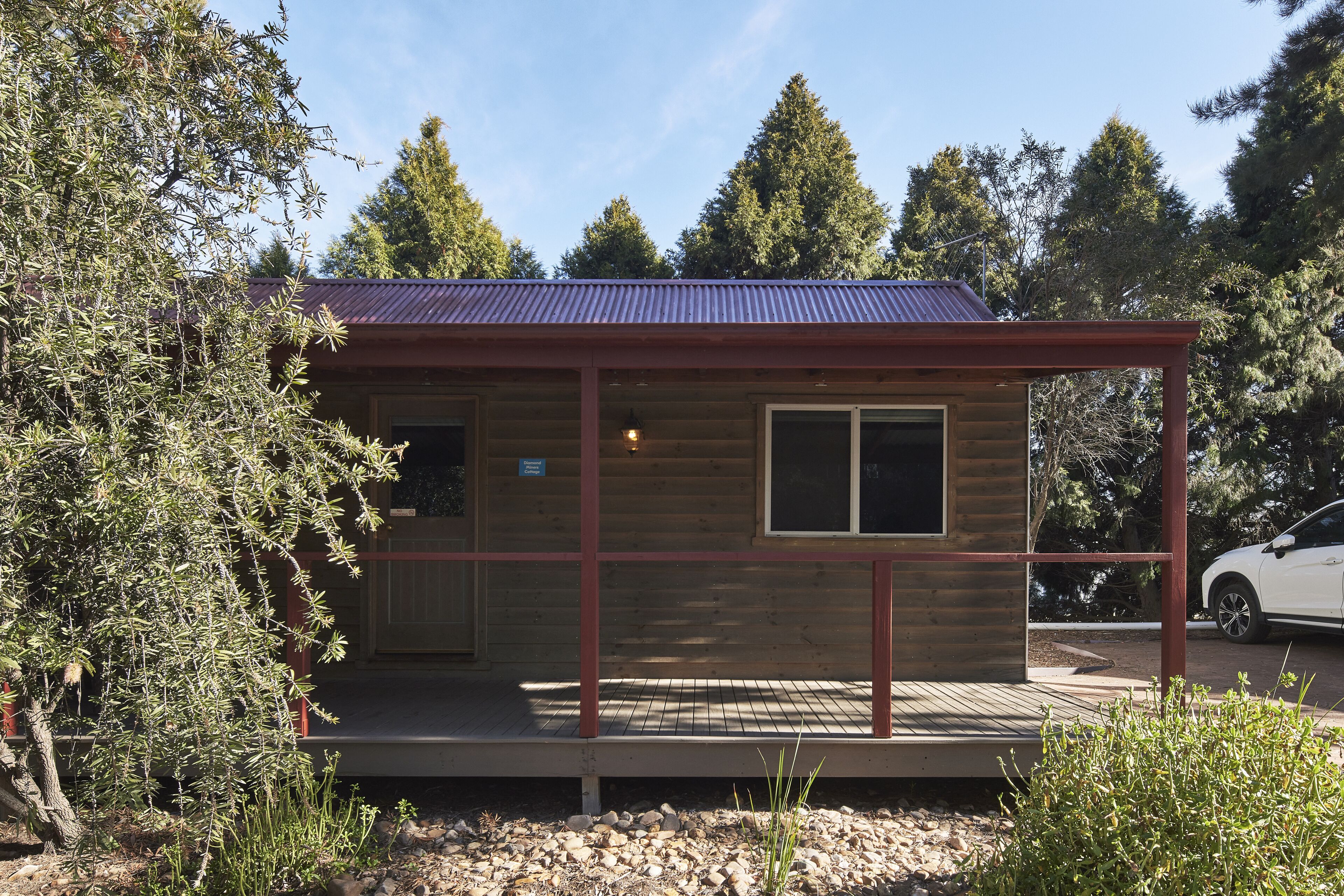 Une petite cabane en bois avec un toit en métal, une véranda et une fenêtre.