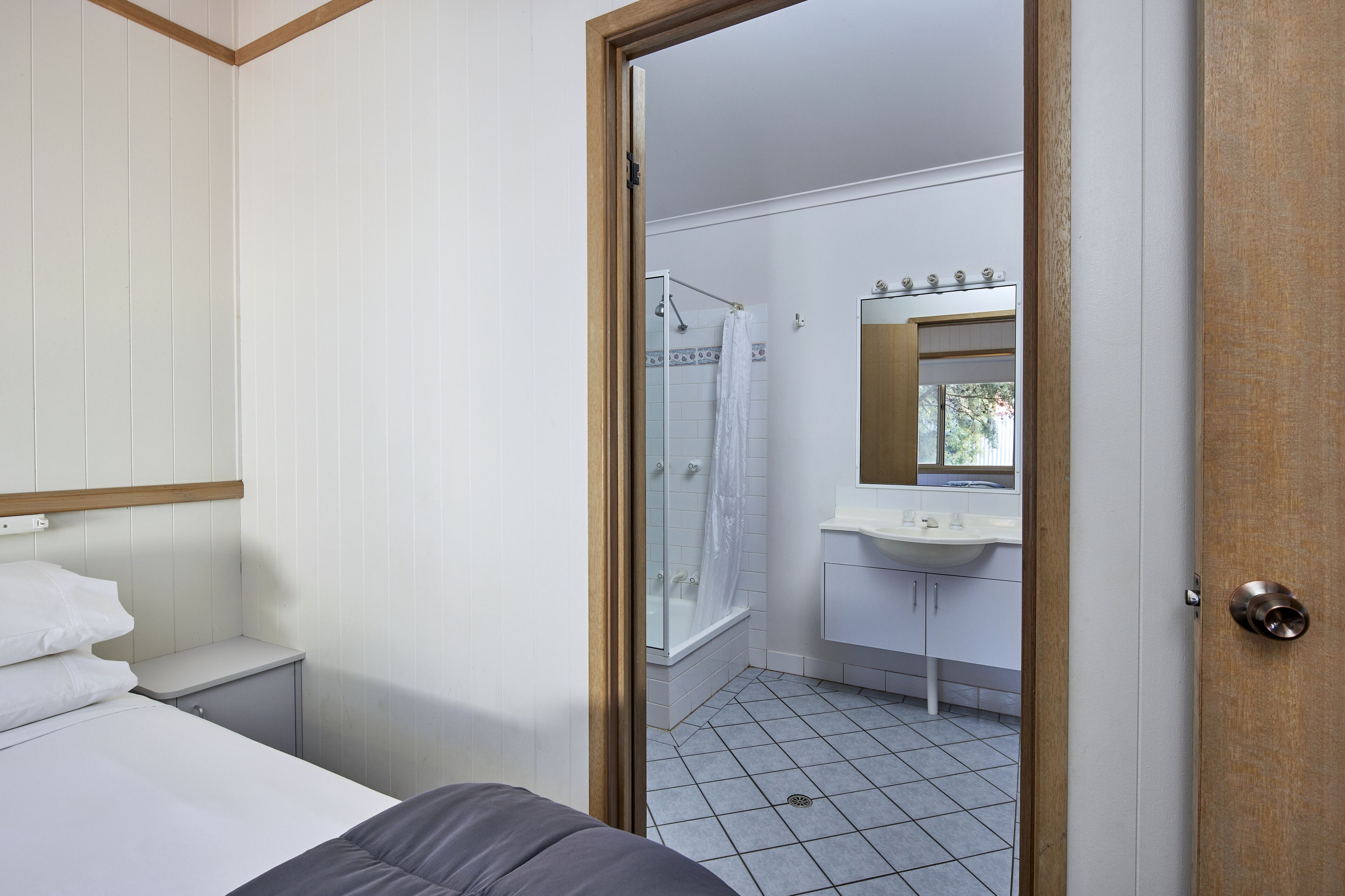 A bedroom with a bed, a nightstand, and a wooden headboard.