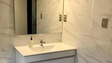 Un bany amb un lavabo blanc, un mirall i parets de marbre.
