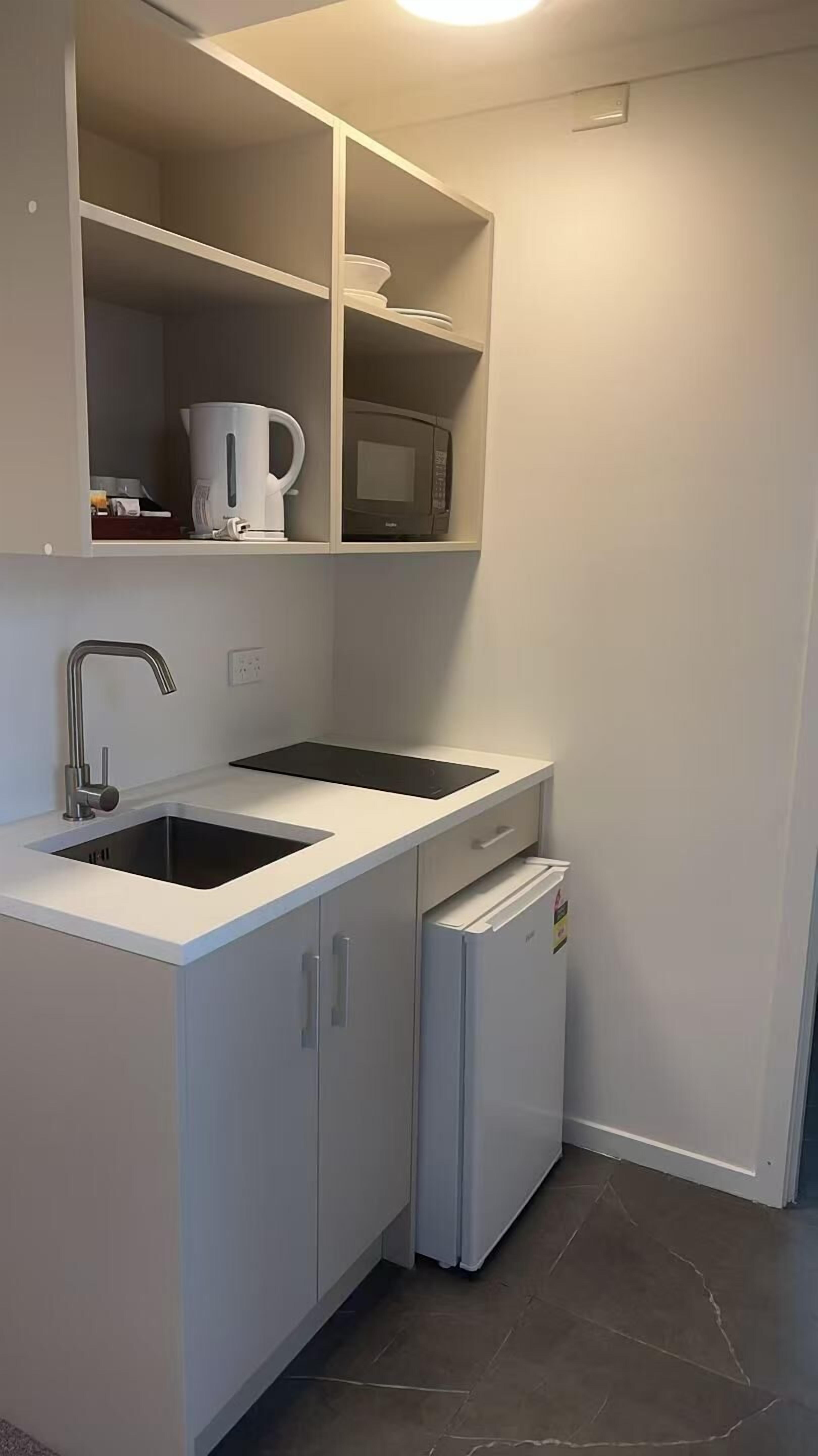Cocina compacta con lavamanos, microondas y refrigerador pequeño.