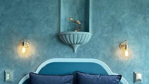 A bedroom with a bed, a wall-mounted mirror, and two wall sconces. - Pure Motel (Rotorua)