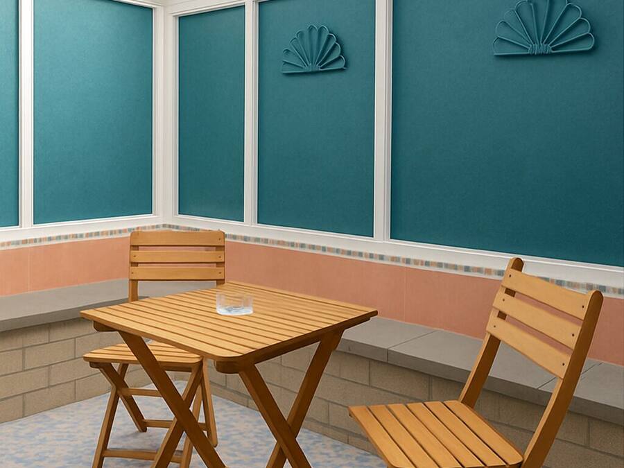 Um alpendre coberto com uma mesa e duas cadeiras, uma parede azul-turquesa decorada com conchas e um chão estampado.