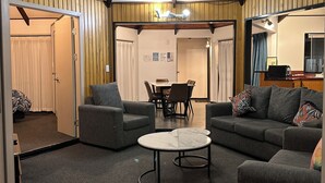 A cozy interior with a high ceiling, wooden panel walls, a dining area, and comfortable seating. - Pure Motel (Rotorua)