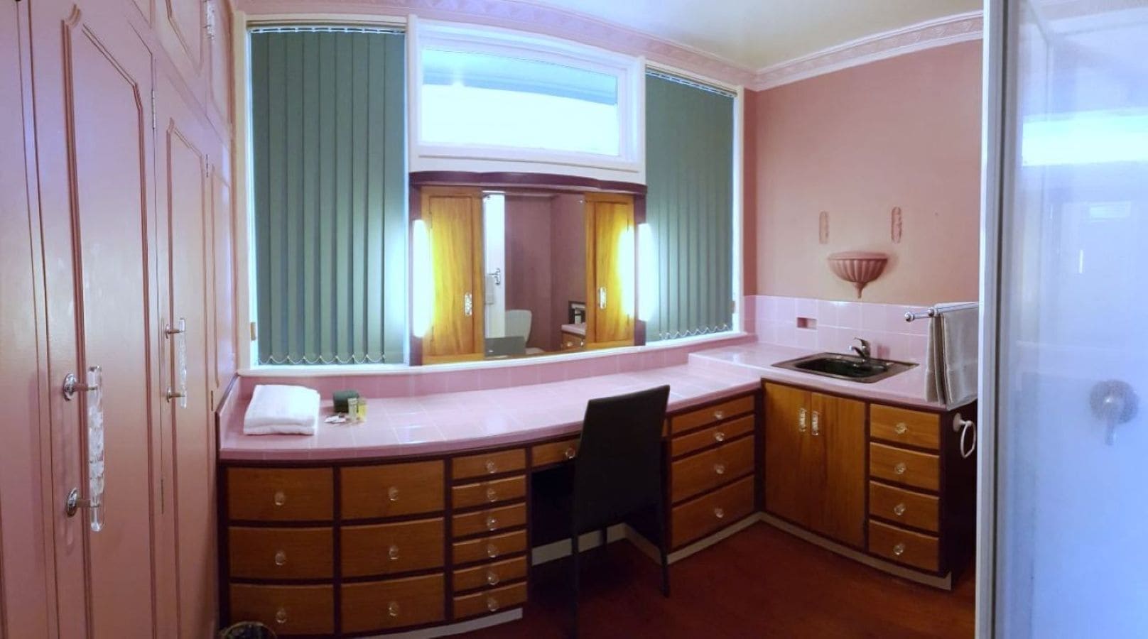 A compact kitchen with a sink, wooden cabinets, and a window with curtains.