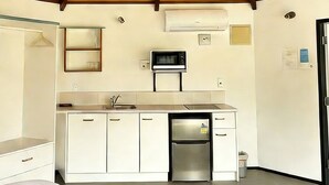 A modern kitchen with a wooden ceiling, white cabinetry, a stainless steel refrigerator, and a microwave. - Pure Motel (Rotorua)