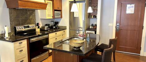 A modern kitchen with a central island, stainless steel appliances, and a wooden cabinet.