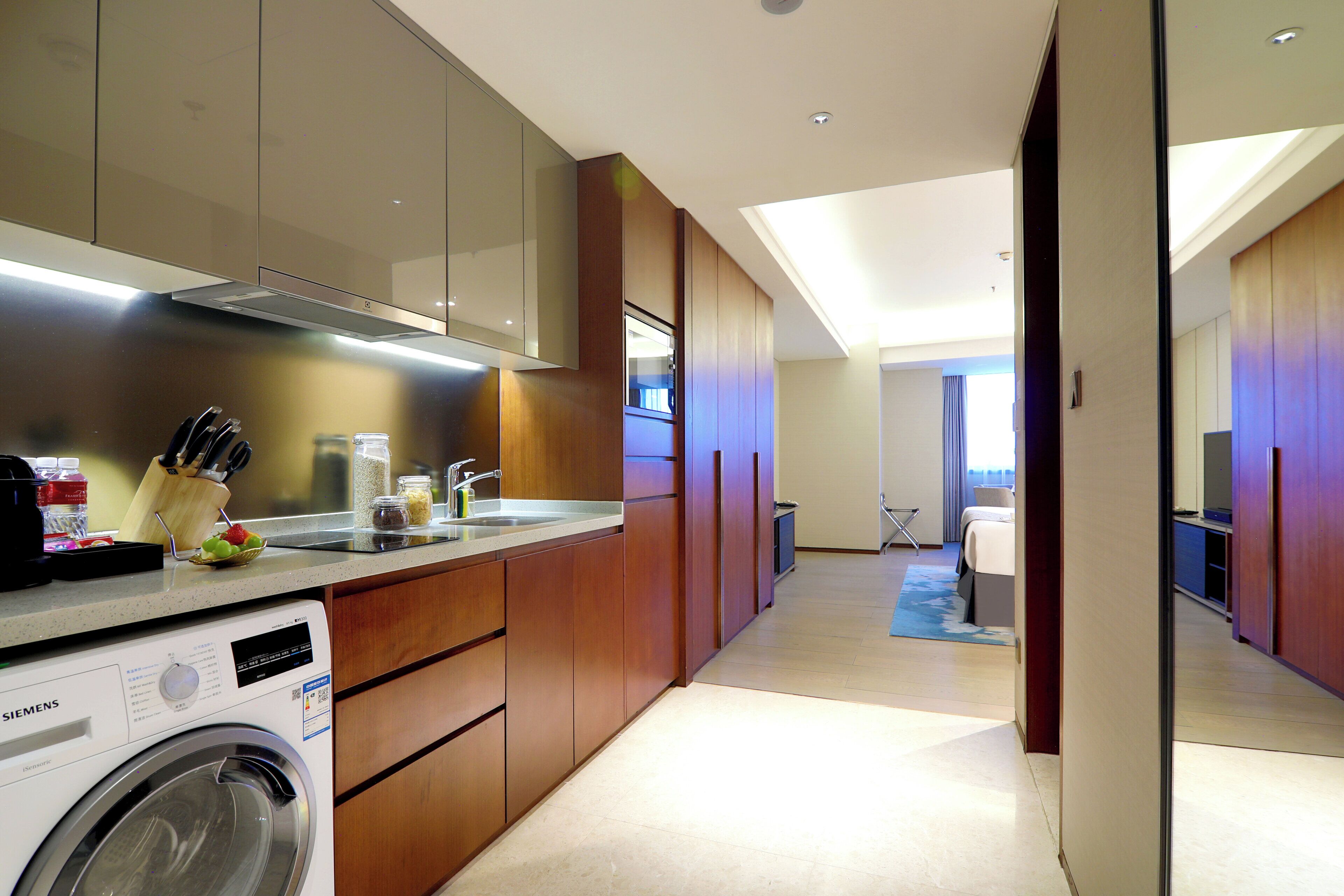 Una habitación de hotel moderna con cocina, lavadora y una cama.