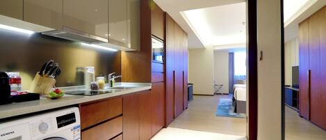 Una habitación de hotel moderna con cocina, lavadora y una cama.