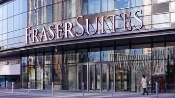 Un edificio moderno con el letrero "FRASER SUNTES", que indica un hotel o establecimiento comercial.