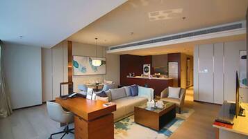 A modern hotel room with a wooden desk, a sofa, a coffee table, and a television.