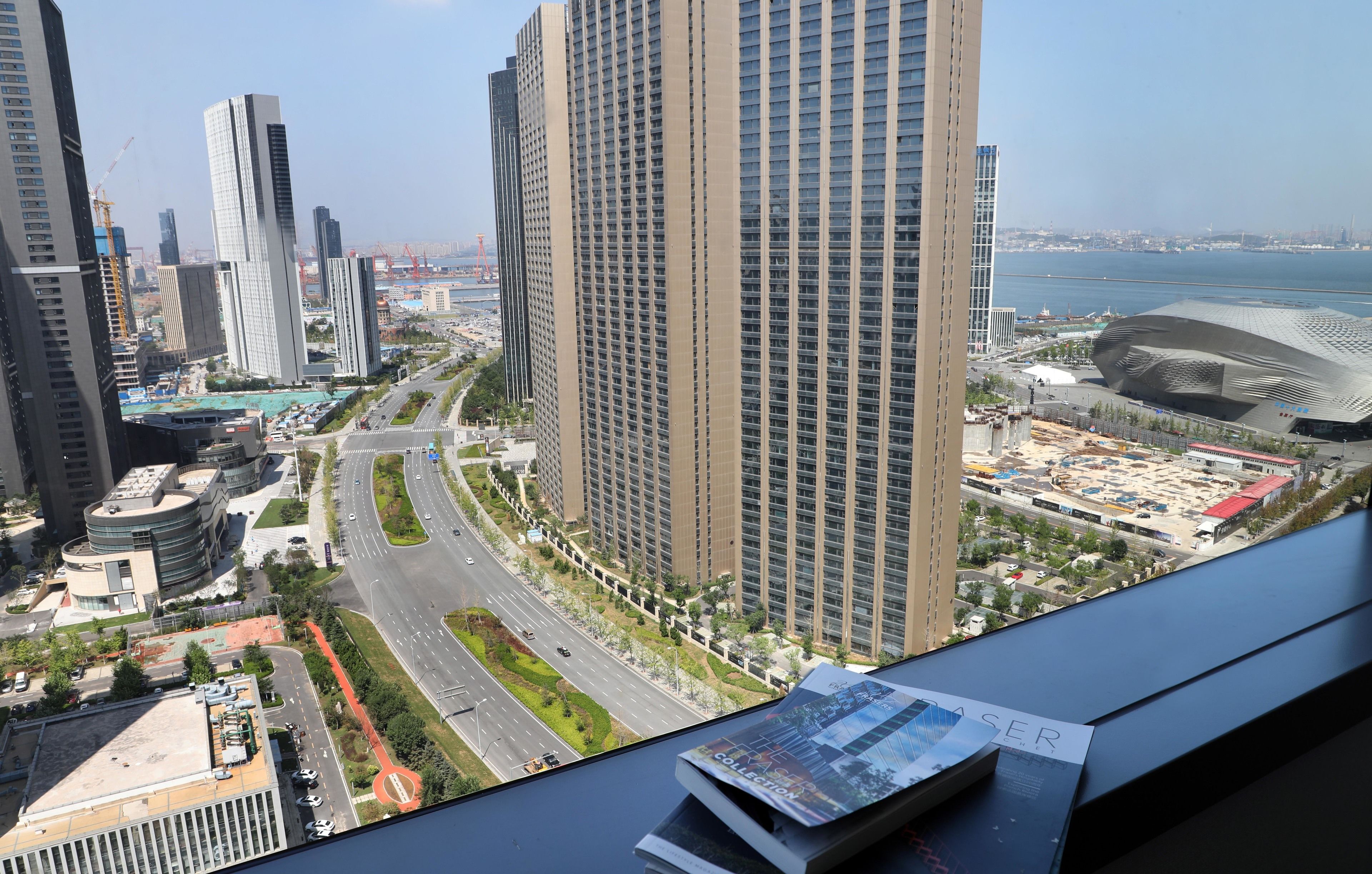 A high-rise building with a modern design, a curved glass facade, and a view of a waterfront.