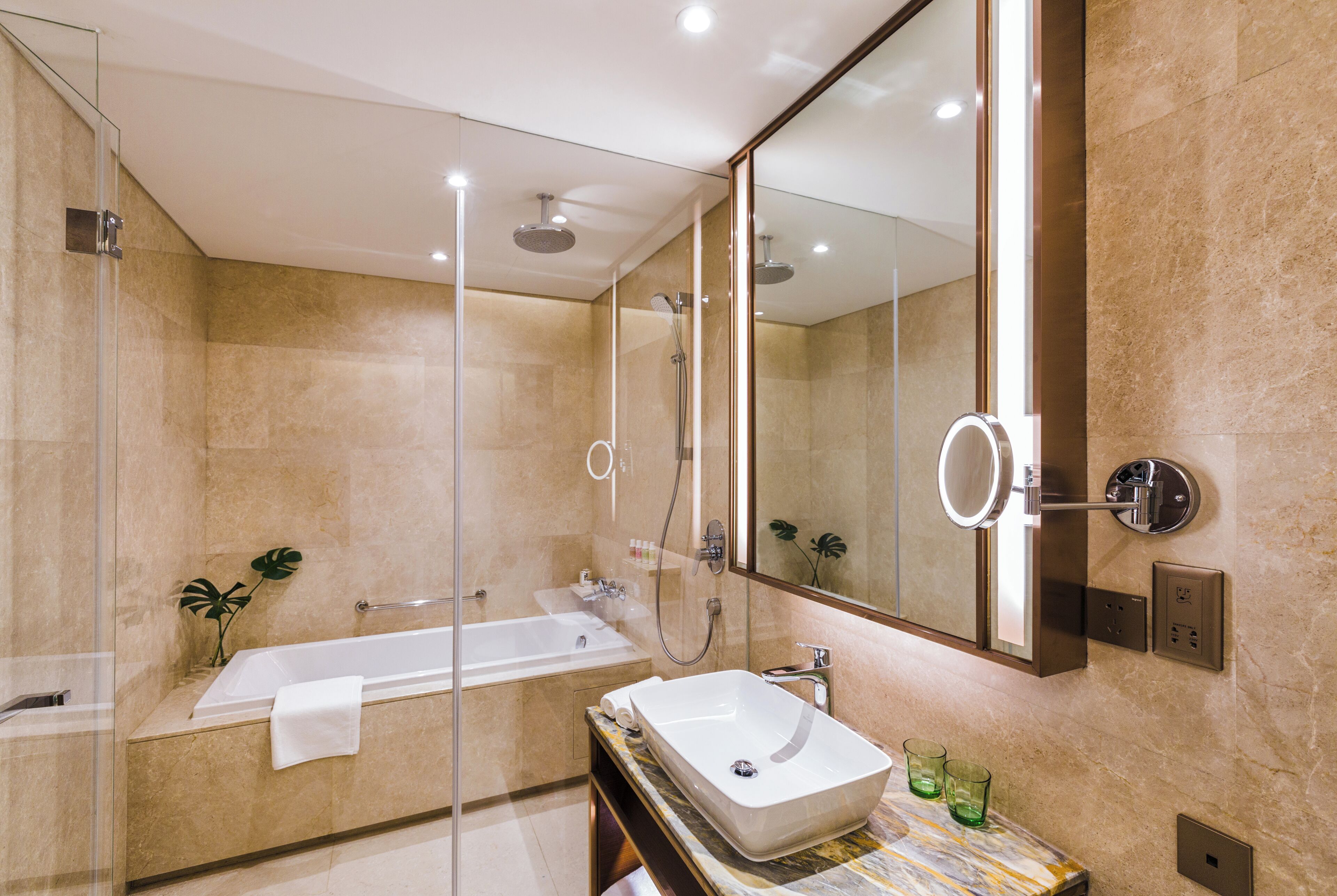 A modern bathroom with a glass-enclosed shower, a freestanding bathtub, and a marble countertop with a sink.