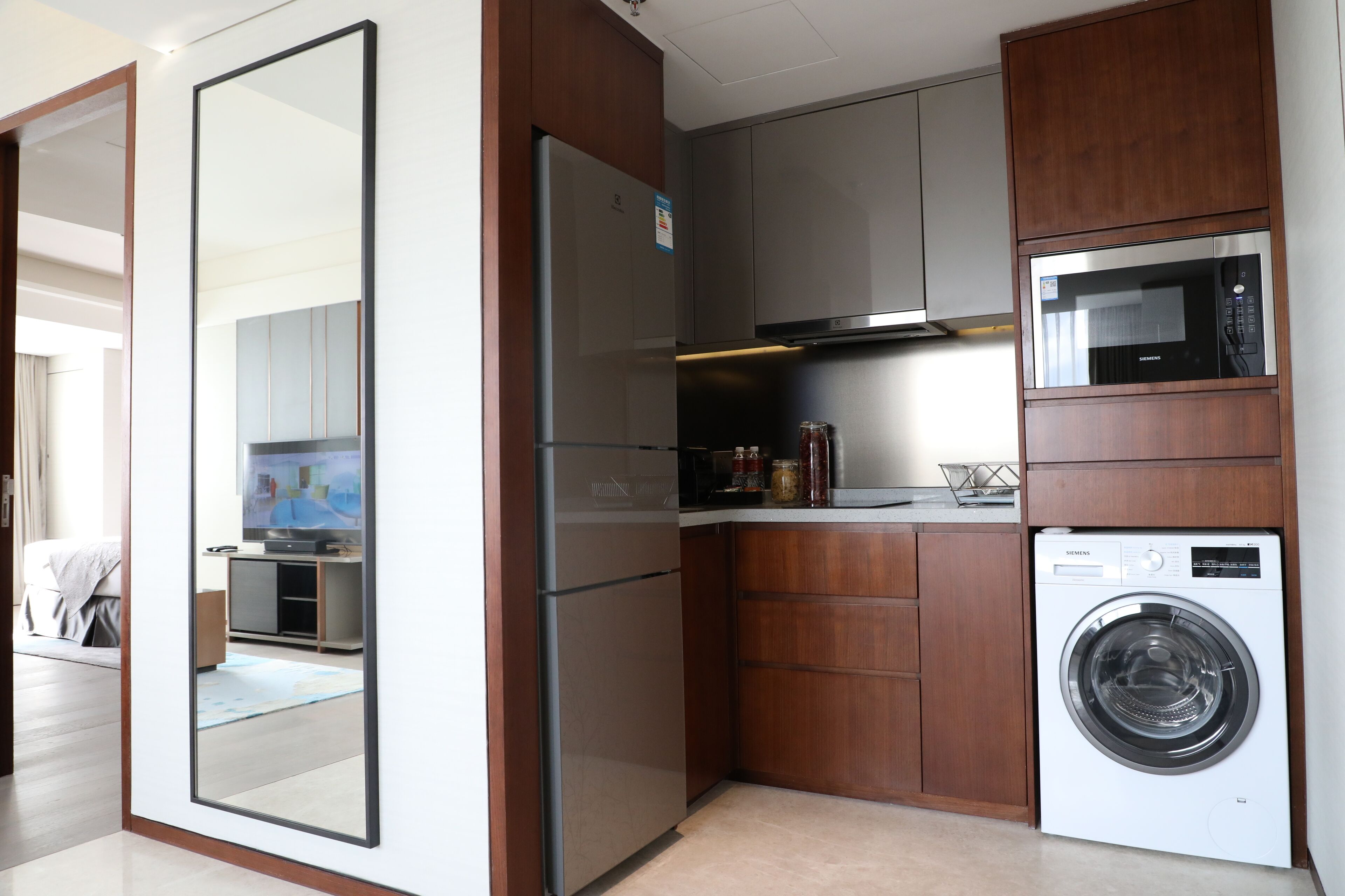 Una cocina compacta con refrigerador, microondas y lavadora.