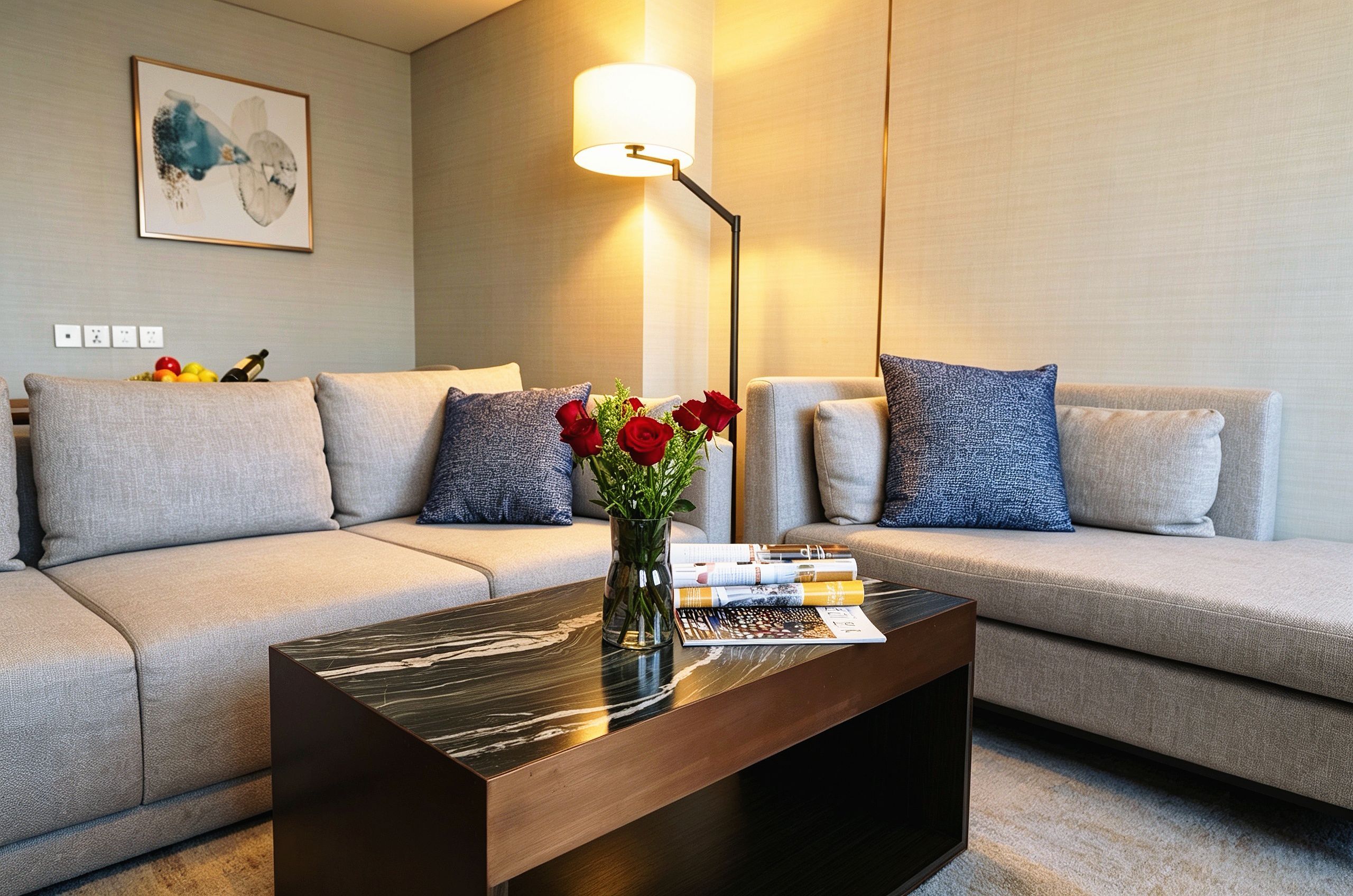 A modern living room with a sofa set, a coffee table with a vase of red roses, and a floor lamp.