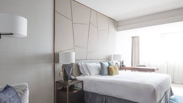 Ein modernes Hotelzimmer mit einem großen Bett, einem Nachttisch mit Lampe, einem kleinen runden Tisch und einer Couch.