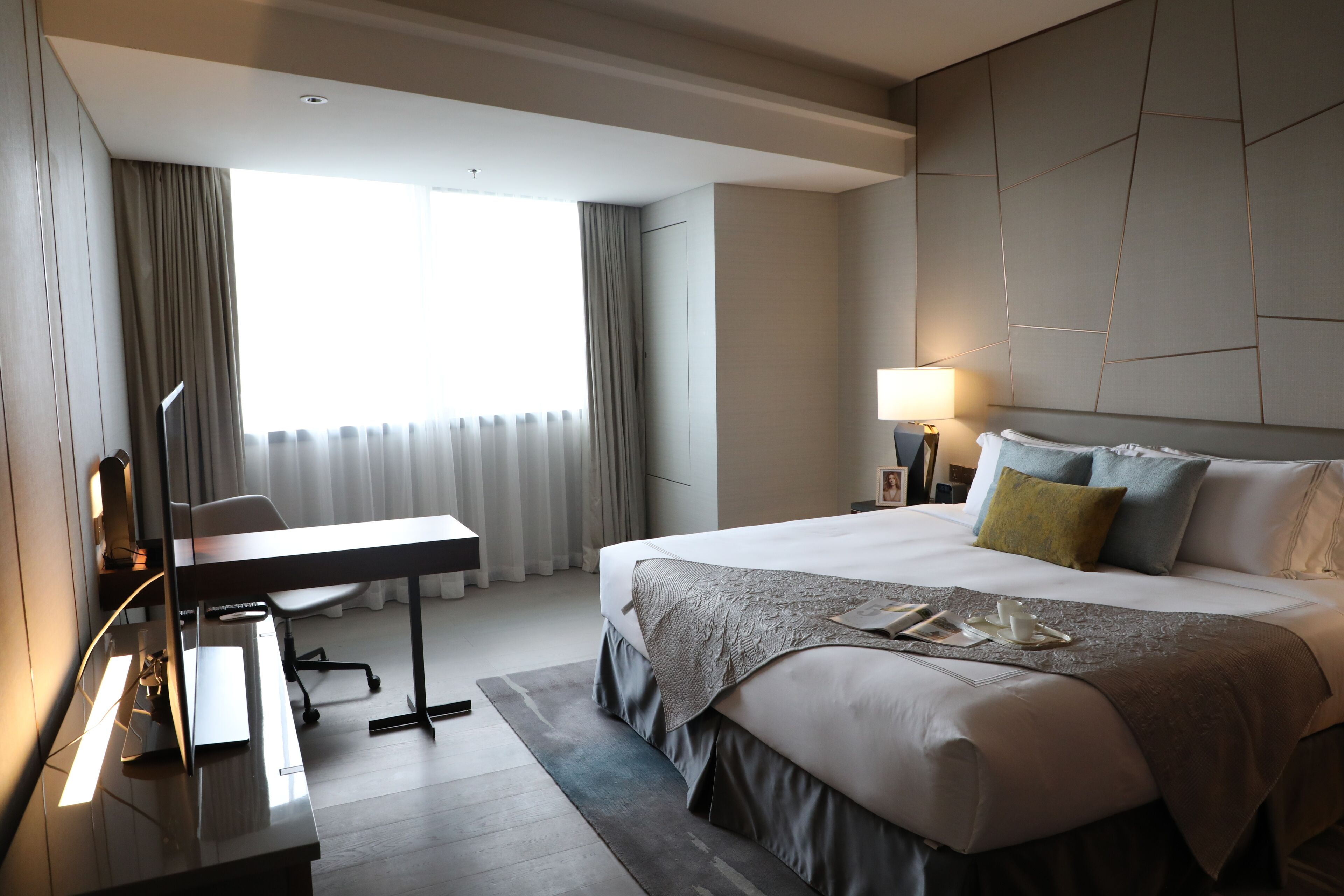 A modern hotel room with a large bed, a desk, and a chair.