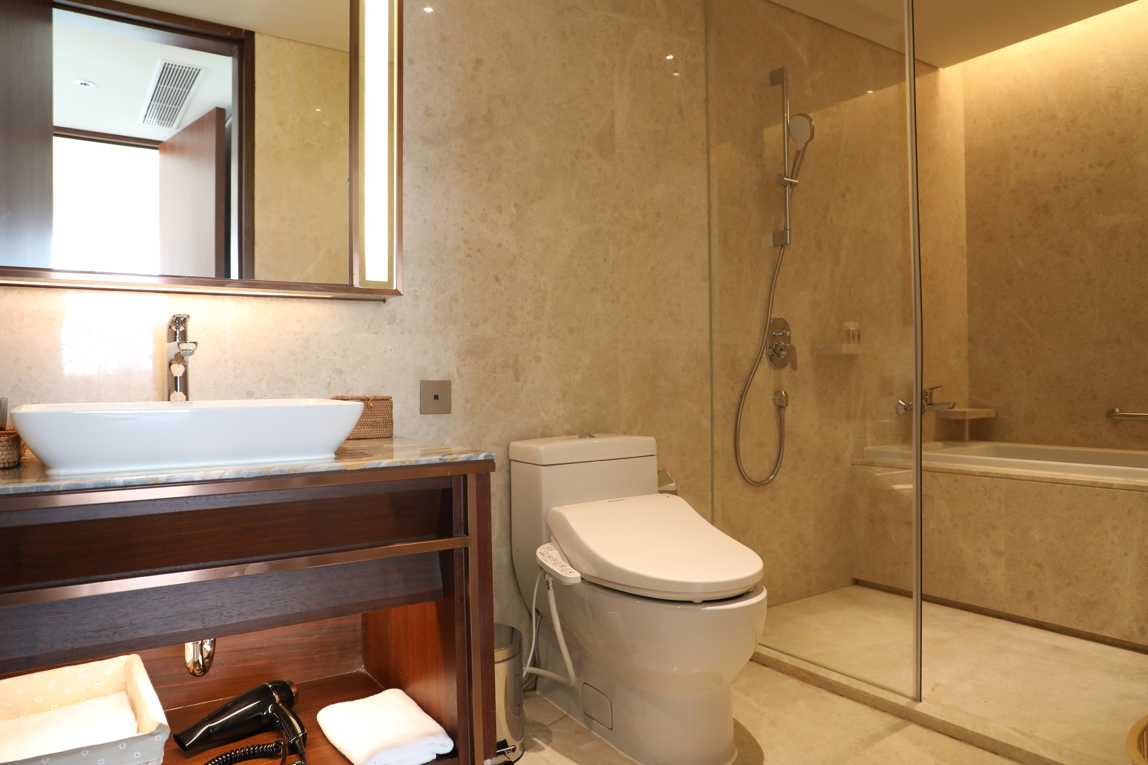 Une salle de bain moderne avec un lavabo blanc, des toilettes et une douche à parois de verre.