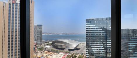 A cityscape with high-rise buildings, a modern stadium, and a body of water.