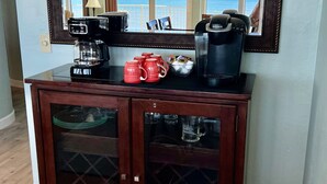 Una kitchenette con cafetera, Keurig y tazas rojas.